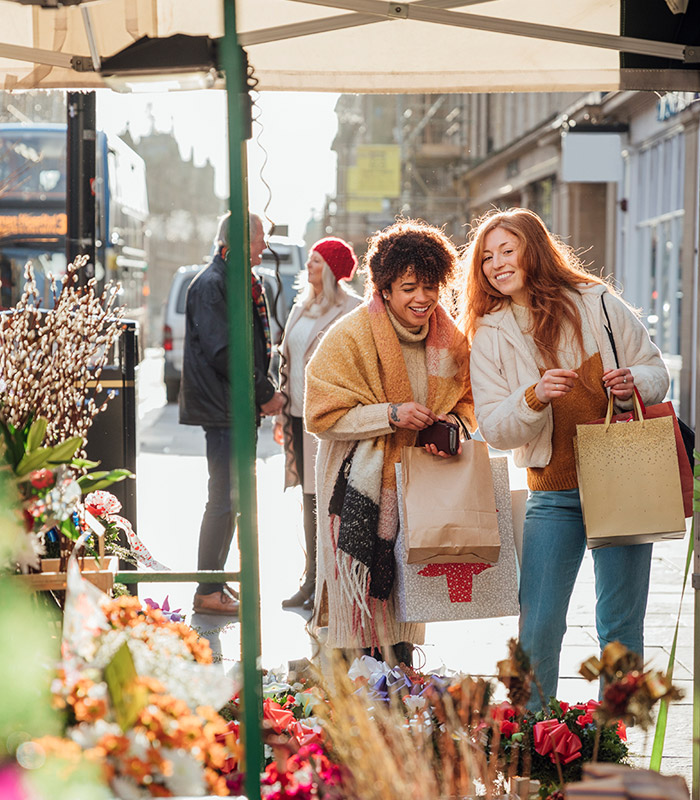 Two women walking along chatting while at a flower market